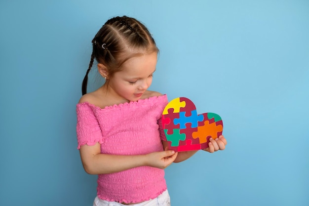 Preschool girl gently holds heartshaped card with puzzles symbol autism