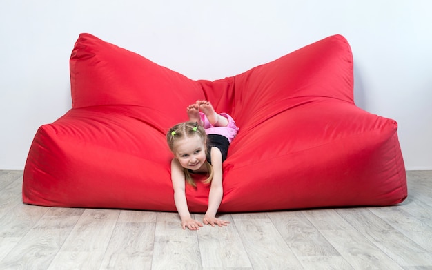 Preschool girl lying on big red sofa