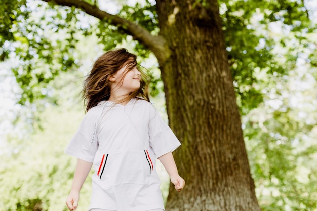 頭を回して夏の公園で楽しんでいる就学前の女の子