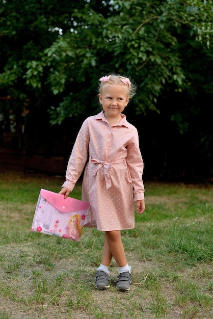 Preschool girl wears a pink dress in white polka dots in the park