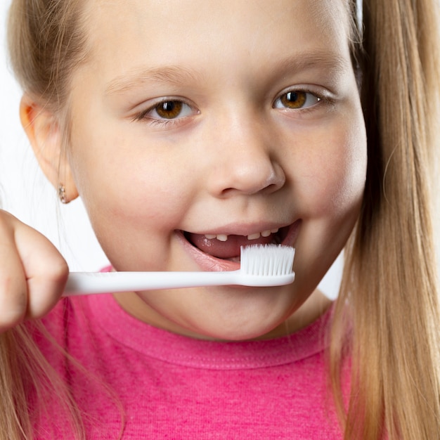 Ragazza in età prescolare con i primi incisivi adulti e uno spazzolino da denti. il dente da latte è caduto e un dente permanente cresce nella bocca aperta. concetto di igiene dentale.