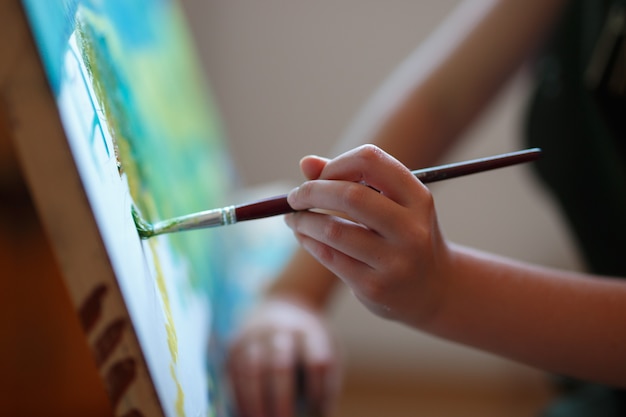 Foto preschool meisje schilderen in de kunstles. close-up foto borstel in de hand.