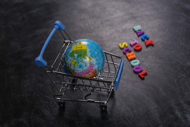 Preschool shopping. Supermarket trolley with globe on chalk board with text Back to School.