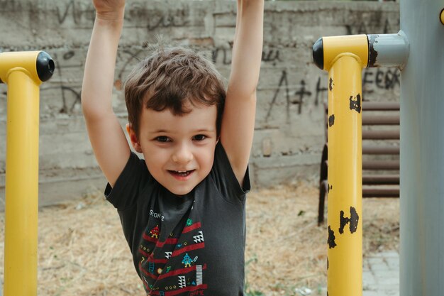 preschooler boy plays on simulators on the playground in the summer