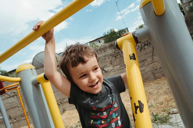 preschooler boy plays on simulators on the playground in the summer