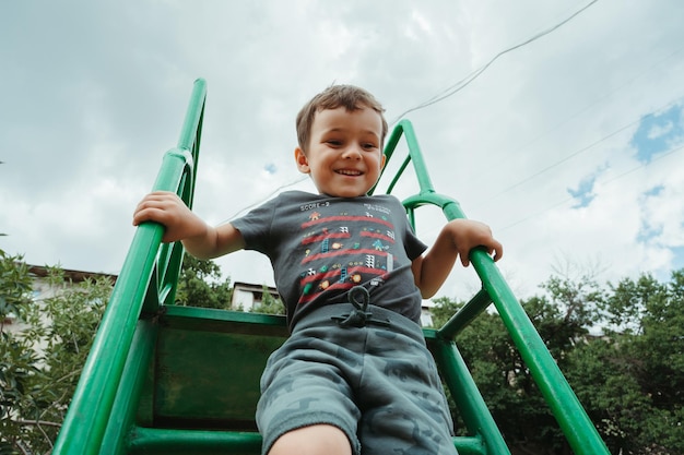 preschooler boy plays on a slide on the playground in the summer