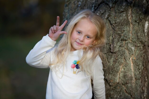 Preschooler girl in the park shows fingers