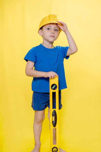 The preschooler in a helmet with a construction level plays a builder