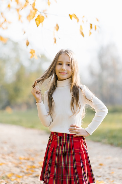 Bambina in età prescolare in un maglione bianco nel parco