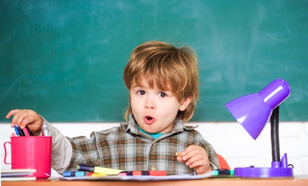 Foto bambino in età prescolare vicino alla lavagna. giovane studente. istruzione e bambini.