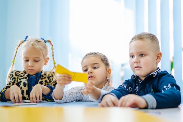Preschoolers sitting at the table in classroom. Kids education concept.