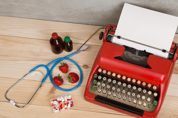 Prescription medicine or medical diagnosis doctor workplace with blue stethoscope pills red typewriter strawberries