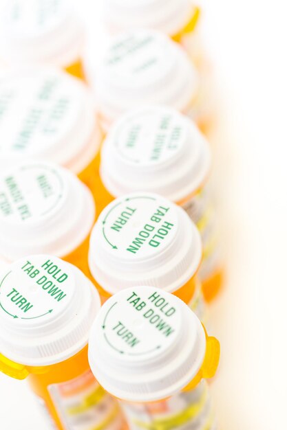 Pillole di prescrizione in bottiglie gialle su sfondo bianco.