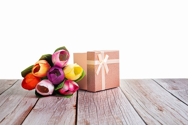 Photo present box and tulips on wooden rustic table with white background with space for text.