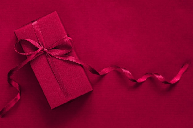 Present box with blue bow on viva magenta background Festive concept Color of the year 2023