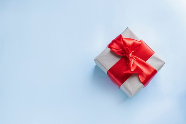 Present box with red bow on light blue background