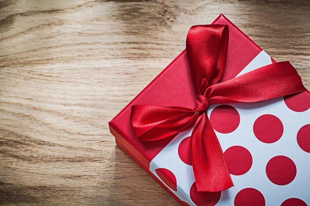 Present box with red bow on wooden board celebrations concept