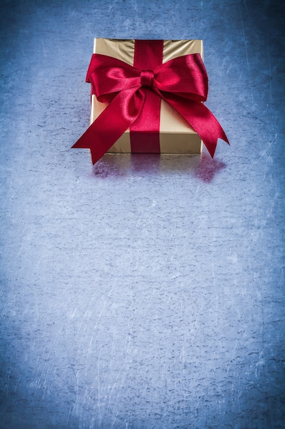 Present box with red ribbon on metallic holiday concept.