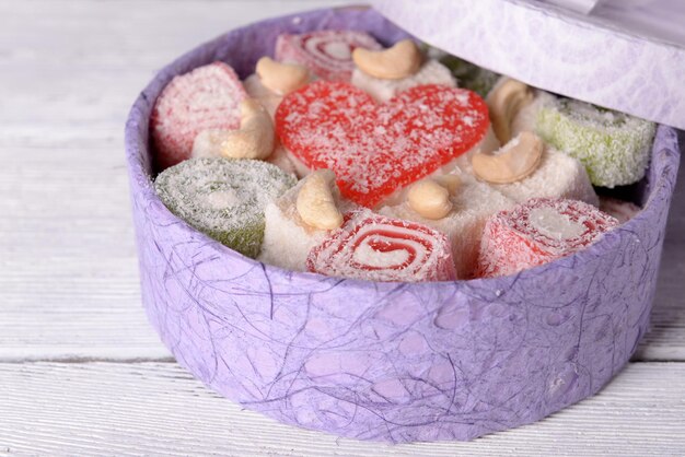 Present box with sweets on wooden background