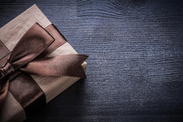 Present boxcontainer with brown tied ribbon on vintage wooden surface