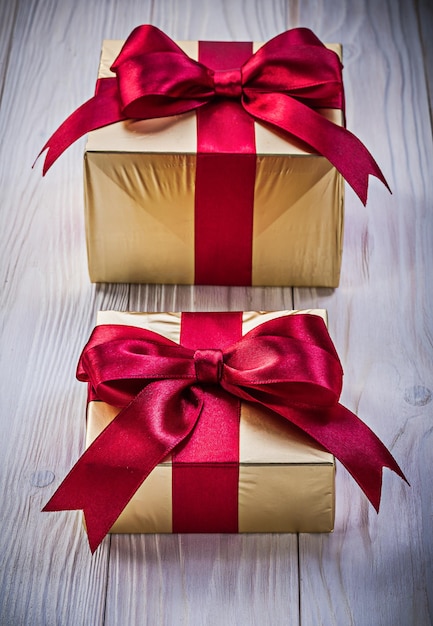 Photo present boxes in golden paper with red ribbons on wooden board holidays concept