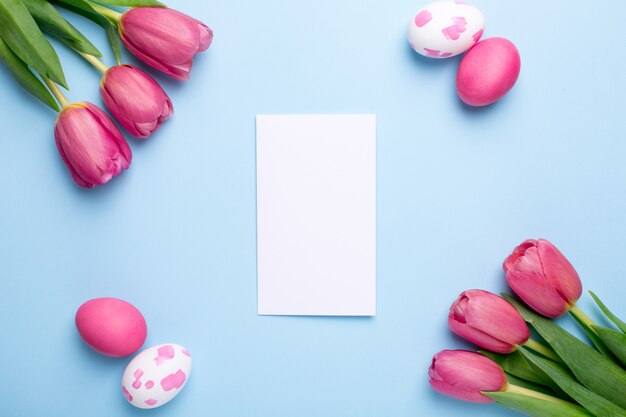 Present card , flowers tulips and easter eggs on a blue surface