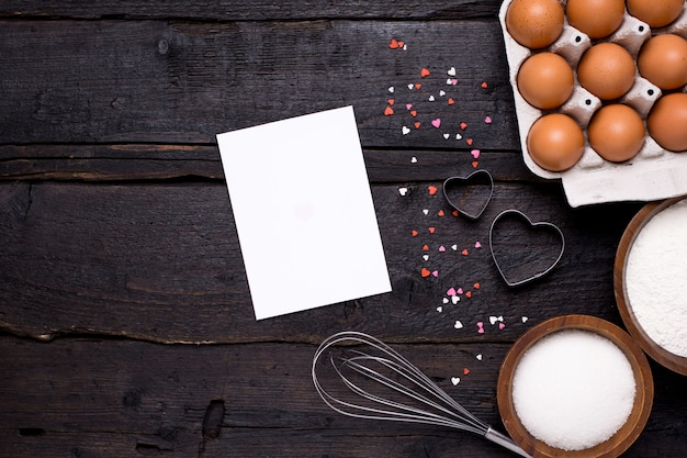 Present card , kitchen tools and hearts on wood