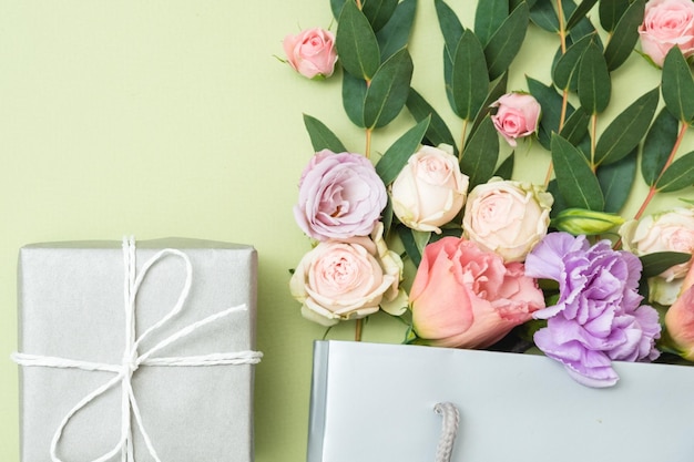 Фото Настоящая доставка подарочная коробка и букет роз на зеленом фоне плоская планировка