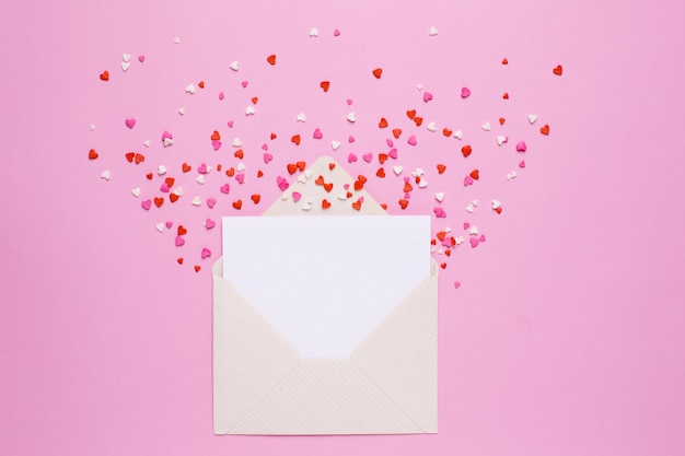 Present envelope and card with pink and red hearts on pink