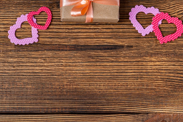 Present gift box with hearts for Valentine day on the wooden background