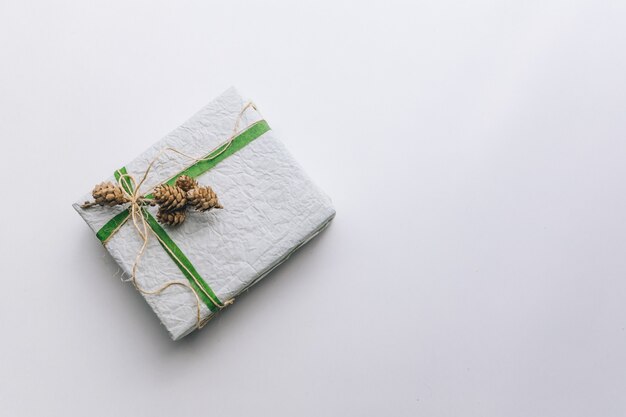 Present gift box wrapped with white paper and green ribbon top view