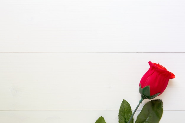 Present gift with red rose flower on wooden table