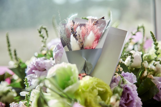 Present post card close up with delicate big flowers bouquet of\
eustoma and dry flowers under day light with dry colorful lagurus\
ovatus grass flowers delivery and present concept high quality\
photo