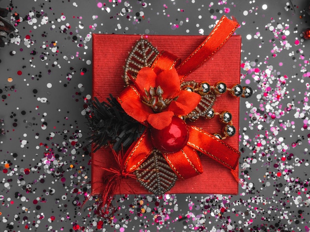 Present or red gift on festive background with confetti sparkles Flat lay trendy style