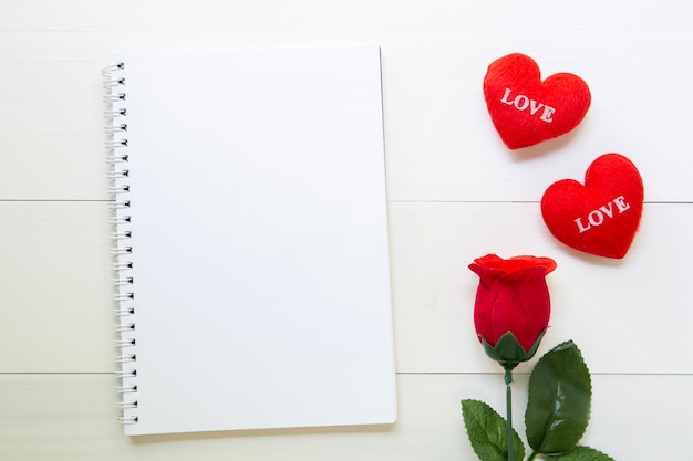 Present red rose flower and notebook and heart shape with copy space on wooden table