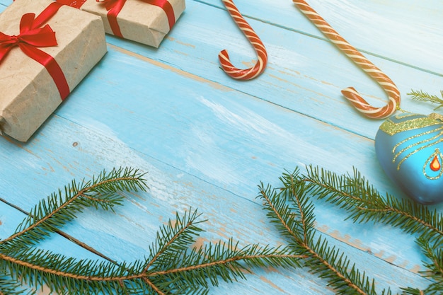 present with red bow with fur spruce pine branches, on the blue painted wooden background