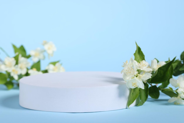 Presentation of product White podium and beautiful jasmine flowers on light blue background closeup Space for text
