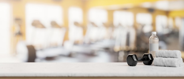 A presentation space on a white table features a dumbbell towels and a water bottle in a fitness