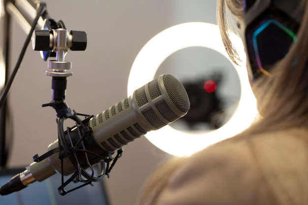 Photo presenter broadcasting her podcast live with a professional microphone and headphones in a small broadcasting studio streaming