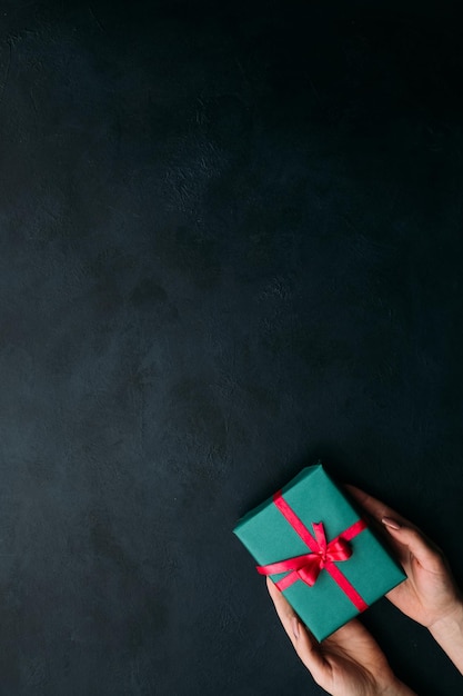Presenteren van een elegant cadeau op donkere achtergrond gesloten geschenkdoos omwikkeld met lint en een strik aangename verrassing voor verjaardag nieuwjaar kerst valentijnsdag en andere feestdagen