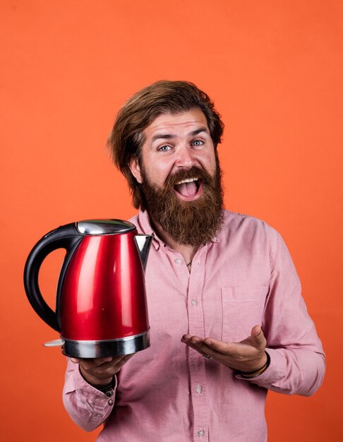 Presenting product casual guy use modern technology in everyday life happy hipster with moustache boil water male householding tea drinking concept bearded man in shirt hold electric kettle