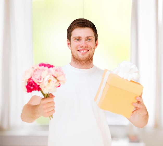 プレゼント、ギフト、お祝い-花の花束とギフトボックスを持っている男
