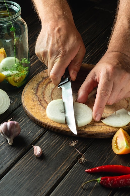 Preservation of vegetables in a jar The chef cuts a ripe onion on a cutting board Peasant food