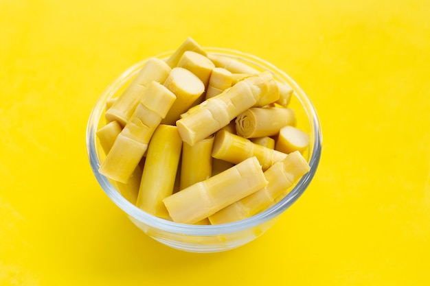 Preserved bamboo shoot in glass bowl on yellow background.