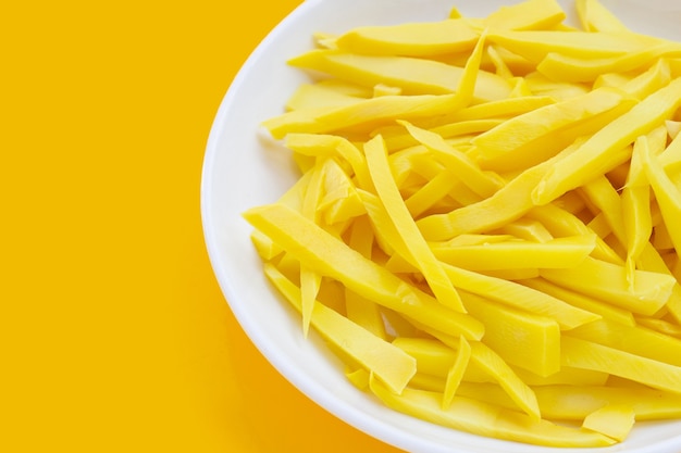 Preserved bamboo shoot in white plate on yellow background.