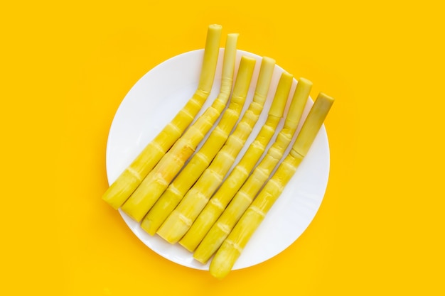 Preserved bamboo shoot in white plate on yellow background.