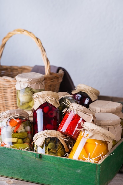 Preserved and fermented local food. Assortment of homemade jars with variety of pickled and marinated vegetables, fruit compote on a wooden table. Housekeeping, home economics, harvest preservation