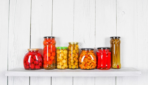 Photo preserved food in glass jars, on wooden shelf. various marinaded food