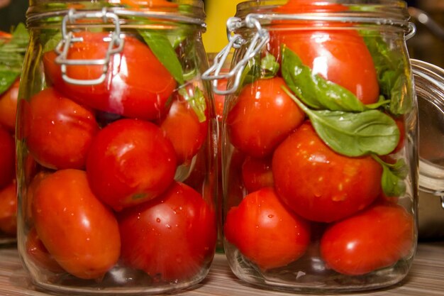 Preserved tomatoes in glass jars on a wooden countertop closeup