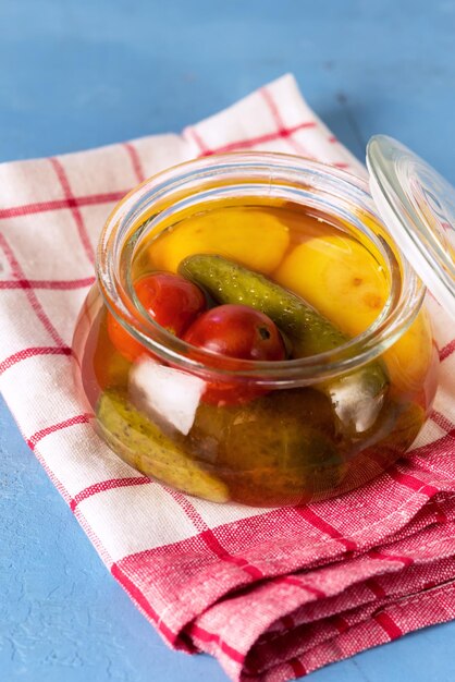 Preserved Vegetables from Vegetables in Glass Jar on a Napkin Blue Background Vertical